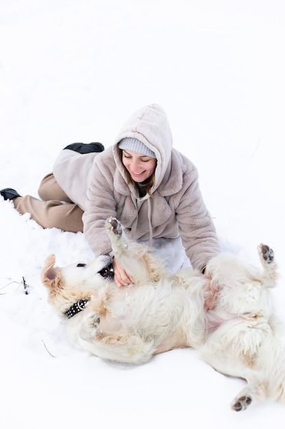 Junge schöne Frau und ihr Golden Retriever Hund haben Spaß im Winter