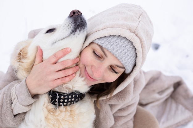 Junge schöne Frau und ihr Golden Retriever Hund haben Spaß im Winter