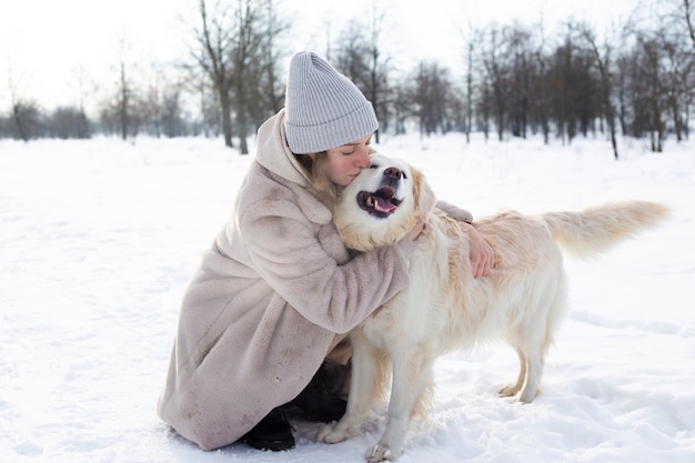 Junge schöne Frau und ihr Golden Retriever Hund haben Spaß im Winter