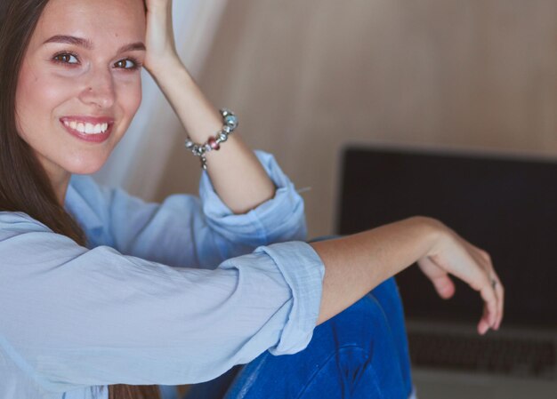 Junge schöne Frau zu Hause auf dem Boden sitzend mit Laptop Junge schöne Frau