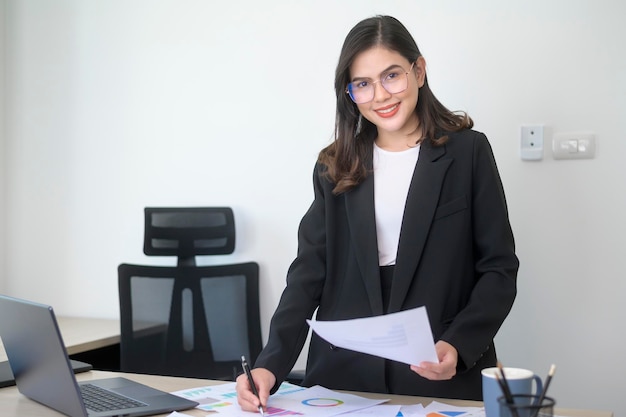 Junge schöne Geschäftsfrau, die am Laptop mit Dokumenten im modernen Büro arbeitet