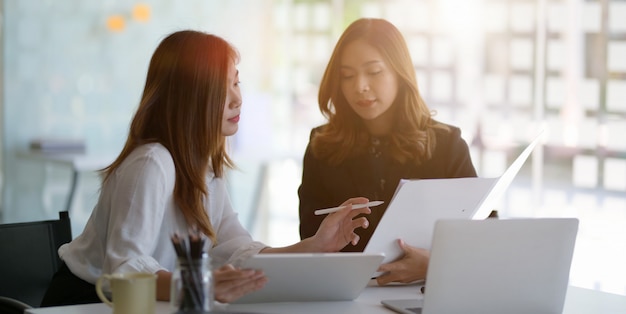 junge schöne Geschäftsfrau, die zusammen das Projekt im modernen Büro bespricht