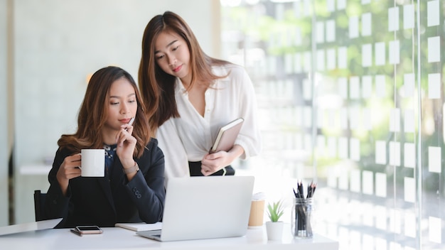 Junge schöne Geschäftsfrauen, die zusammen an dem Projekt arbeiten