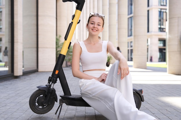 Junge schöne glückliche Frau, die Elektroroller in der Stadt reitet und lächelt Elektrischer Öko-Sharing-Transport