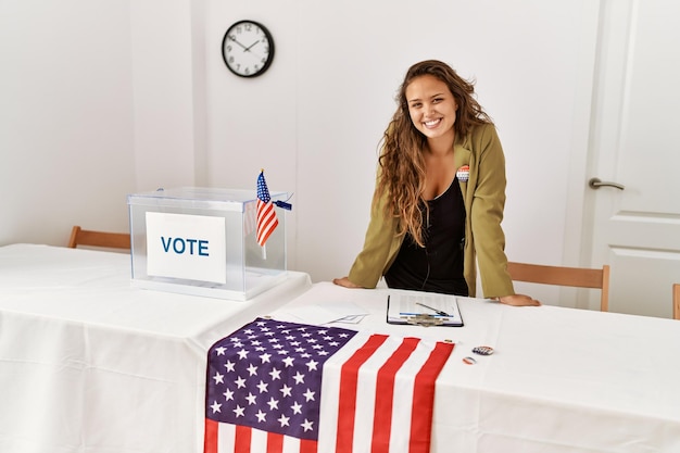 Junge schöne hispanische Wahlpräsidentin lächelt selbstbewusst im Wahlkollegium