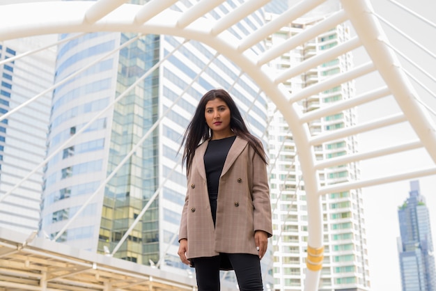 Junge schöne indische Geschäftsfrau an der Skywalkbrücke