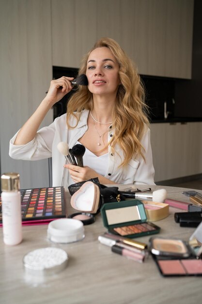 Junge schöne kaukasische Frau, professionelle Beauty-Bloggerin oder Vloggerin, schreibt Make-up-Tutorial, um es in sozialen Medien zu teilen. Sie erklärt, wie man Pinsel verwendet. Online-Lernkonzept