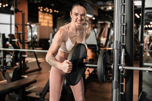 Junge schöne, kaukasische, starke Frau macht Übungen im Fitnessstudio