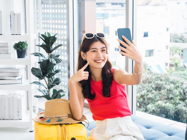 Junge schöne lächelnde asiatische Frau, die ein intelligentes Mobiltelefon hält und ein Selfie mit der Kamera macht