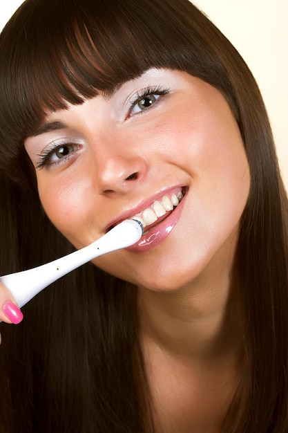 Junge schöne lächelnde Frau mit den großen weißen Zähnen, die eine Zahnbürste halten