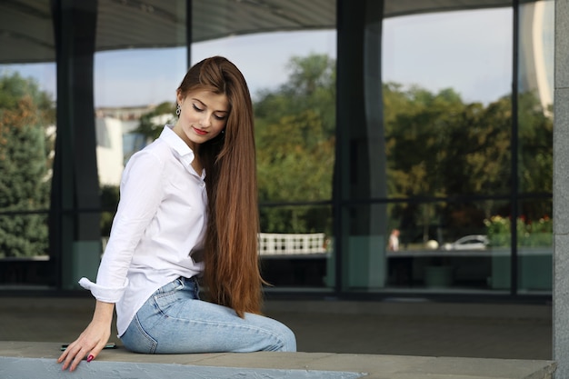 Junge schöne lächelnde Frau mit langen glatten Haaren sah nach unten