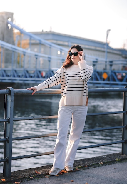 Junge schöne lächelnde Hipster-Frau in trendiger Sommerkleidung Sexy sorgloses Modell, das bei Sonnenuntergang auf dem europäischen Straßenhintergrund posiert Positive brünette Frau Fröhlich und glücklich