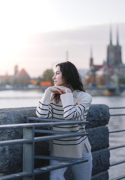 Junge schöne lächelnde Hipster-Frau in trendiger Sommerkleidung Sexy sorgloses Modell, das bei Sonnenuntergang auf dem europäischen Straßenhintergrund posiert Positive brünette Frau Fröhlich und glücklich