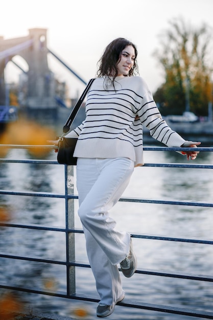 Junge schöne lächelnde Hipster-Frau in trendiger Sommerkleidung Sexy sorgloses Modell, das bei Sonnenuntergang auf dem europäischen Straßenhintergrund posiert Positive brünette Frau Fröhlich und glücklich