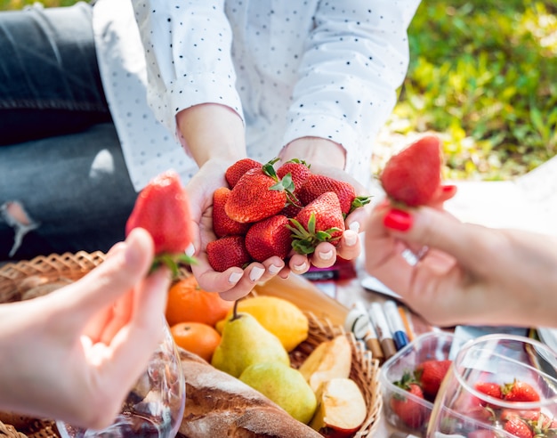 Junge schöne Mädchen, die Erdbeeren im Park essen