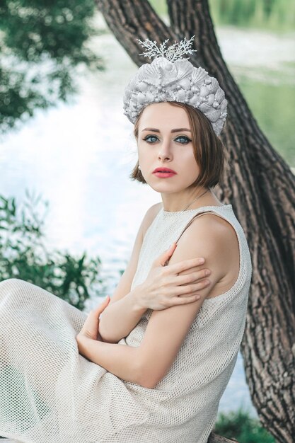 Foto junge schöne meerjungfrau in muschelkrone sitzt auf dem wasser-hintergrund meerjungfrau-cosplay