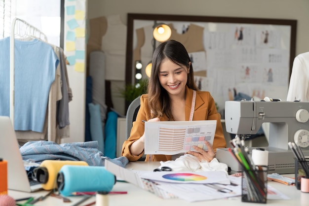 Junge schöne Modedesignerin arbeitet mit farbigen Textilproben im Atelier