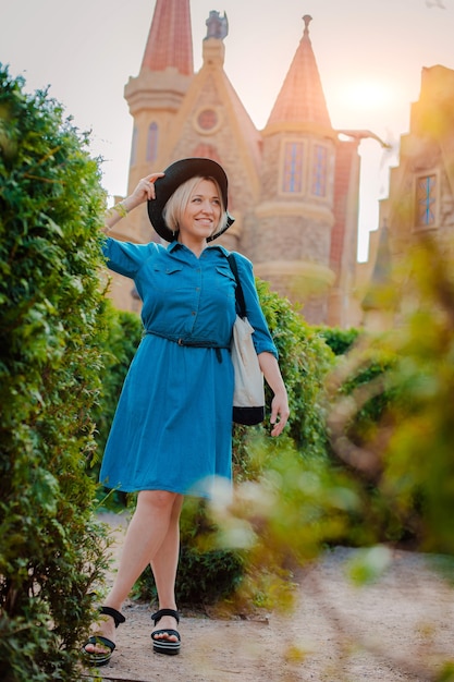 Junge schöne modische glückliche Frau des Porträts in einem schwarzen Hut in der mittelalterlichen Altstadt.