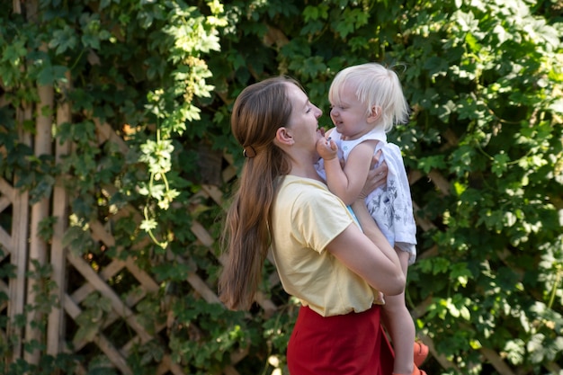 Junge schöne Mutter hält Kind in ihren Armen. Porträt von Mutter und Kleinkind im Freien.