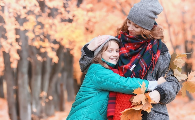 Junge schöne Mutter mit ihrer Tochter auf Natur. Ein Mädchen mit Hut geht im Park spazieren. Mädchen im Herbststadtpark im Blattfall.