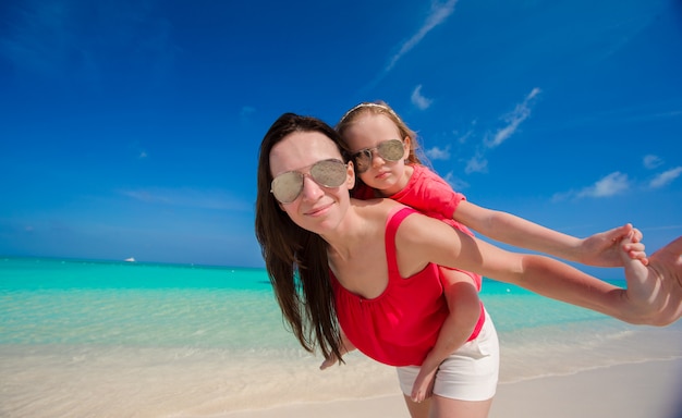 Junge schöne Mutter und ihre entzückende Tochter haben Spaß am tropischen Strand