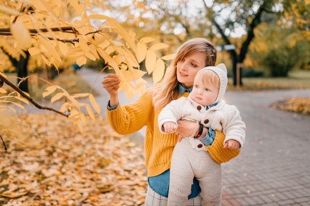 Junge schöne mutter verbringt gerne zeit im herbstpark mit ihrem kleinen kind.