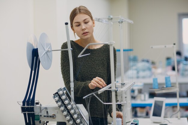 Junge schöne Näherin näht an Nähmaschine in Fabrik.