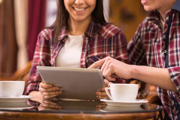 Junge schöne Paare am Café benutzen Tablette.