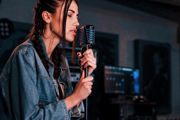 Junge schöne Sängerin probt in einem Tonstudio