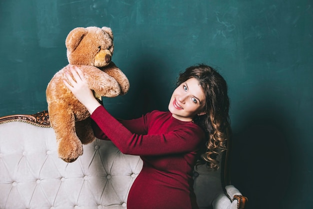 Foto junge schöne schwangere frau zu hause mit einem teddybären in den händen