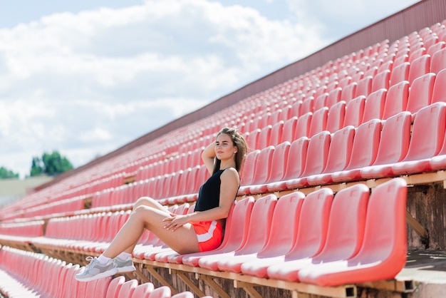 Junge, schöne Sportlerin in Sportbekleidung trainiert und läuft und streckt sich im Stadion