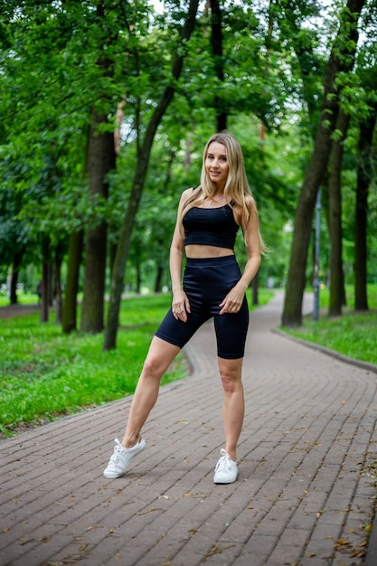 Junge schöne sportliche blonde Frau in einem schwarzen T-Shirt und in schwarzen engen Sportshorts