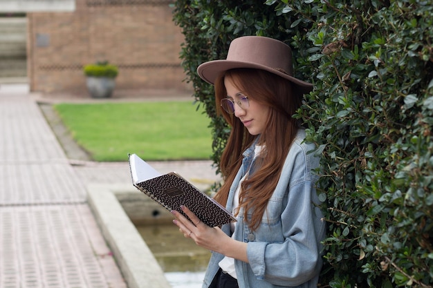 junge schöne Studentin liest ein Buch in einem Park in einer Universitätsbibliothek