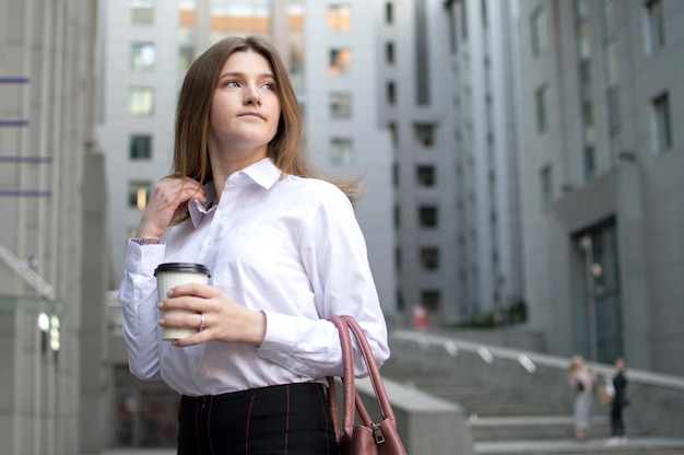 Junge schöne Studentin steht mit Kaffee