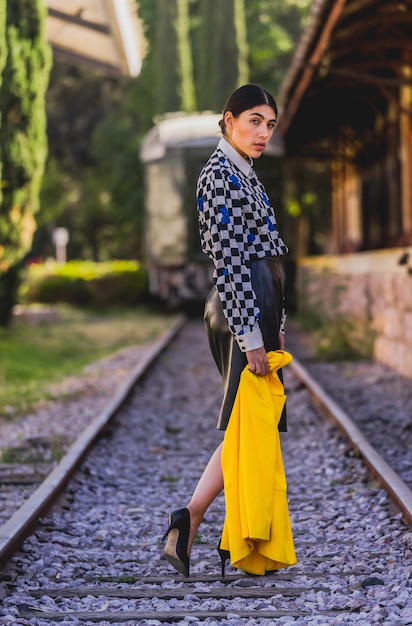 Junge schöne Touristenfrau im Retrostil im alten Bahnhof, tragende gelbe Jacke und Schwarzes.