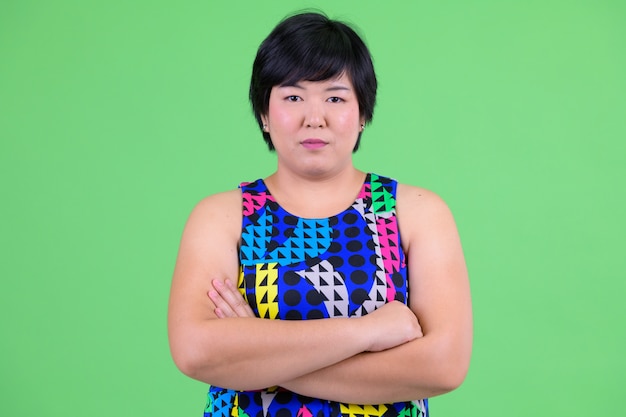 junge schöne übergewichtige asiatische Frau bereit, gegen Chroma Key mit grüner Wand zu feiern