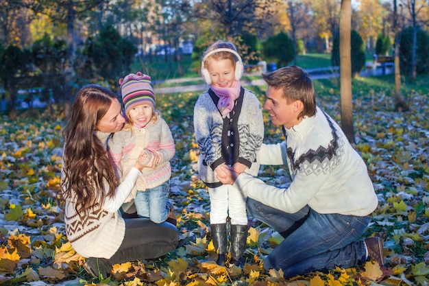 Junge schöne vierköpfige Familie genoss, im Herbstpark sich zu entspannen