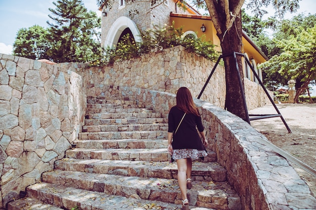 Junge schönheit, die herauf die steintreppe mit natürlichem hintergrund geht. schritt für erfolgskonzept.