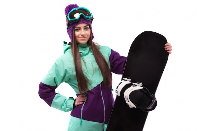 Junge Schönheit im purpurroten Skimantel und in den Schutzbrillen halten Snowboard