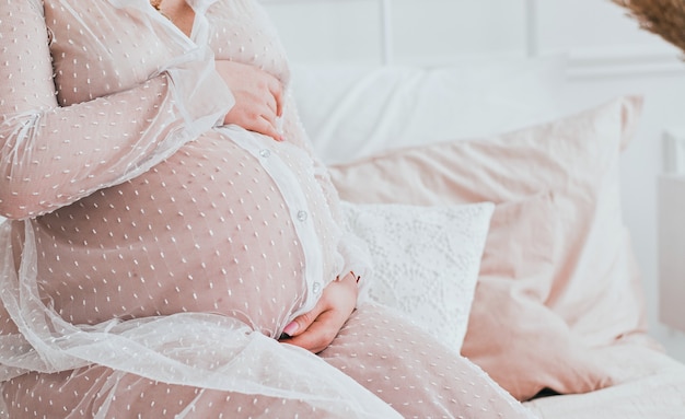 Junge schwangere Frau, die auf Sofa nah oben sitzt