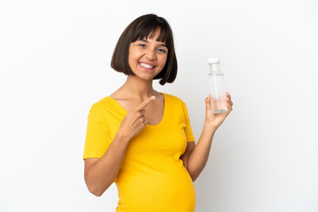 Junge schwangere Frau, die eine Flasche Wasser isoliert auf weißem Hintergrund hält und auf die Seite zeigt, um ein Produkt zu präsentieren