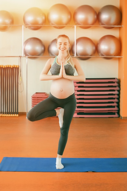 Junge schwangere Frau, die Yoga tut