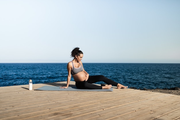 Junge schwangere Frau macht Yoga im Freien