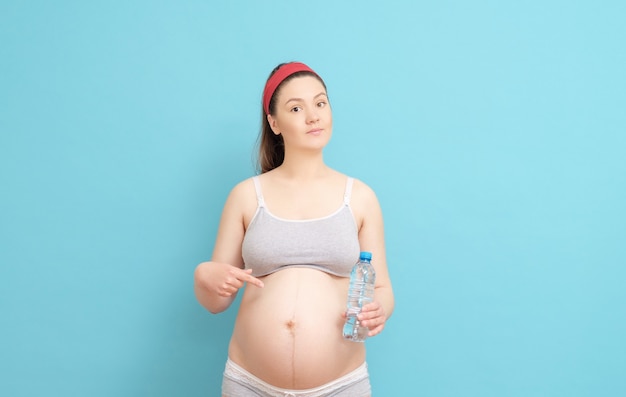 Junge schwangere Frau mit Flasche Wasser