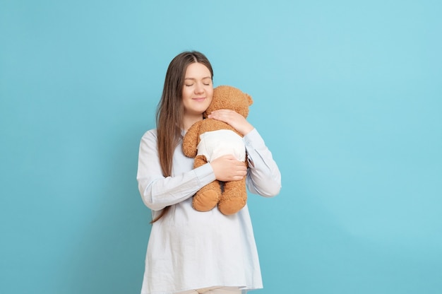 Junge schwangere Frau mit Teddybär in den Händen