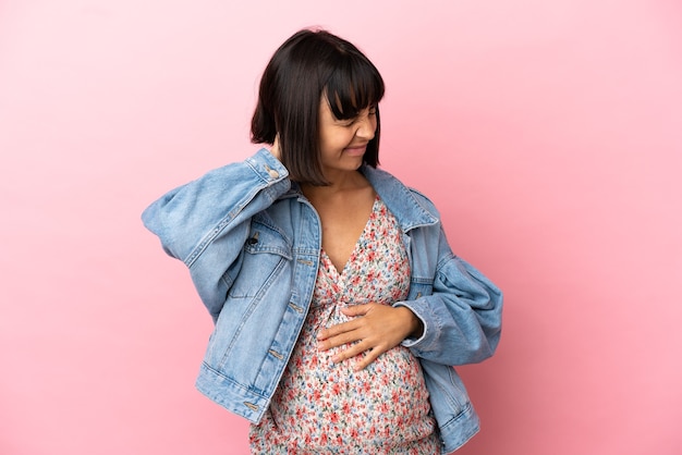 Junge schwangere Frau über isoliertem rosa Hintergrund mit Nackenschmerzen
