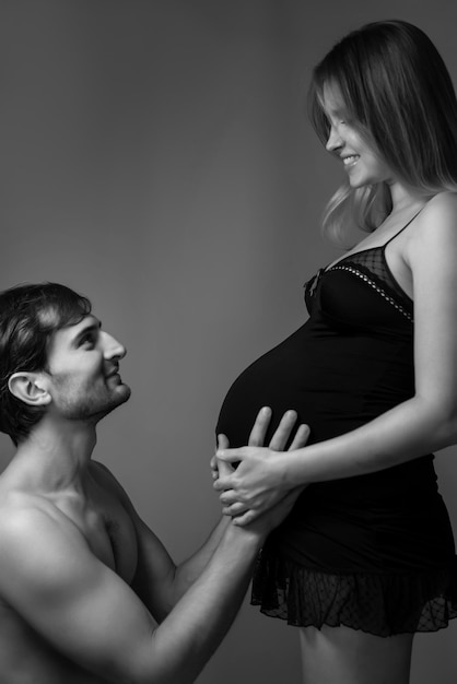 Junge schwangere Frau und glücklicher Mann im Hintergrund