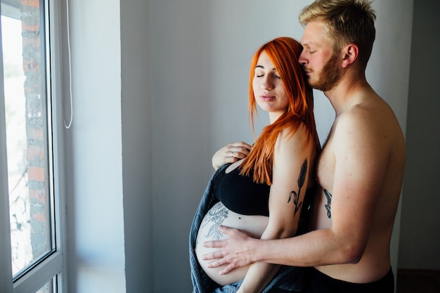 Junge schwangere Paar kuscheln zu Hause