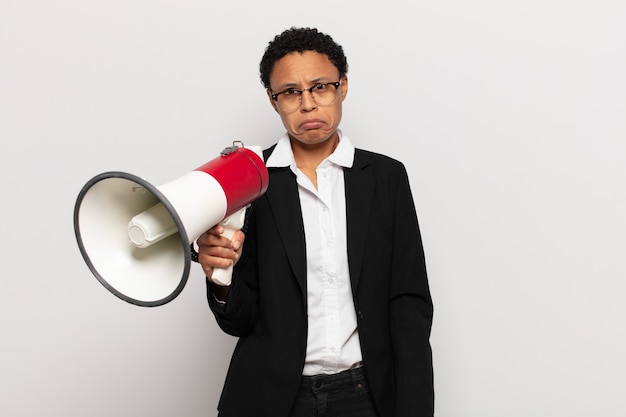 junge schwarze Afro-Frau, die sich traurig und weinerlich mit einem unglücklichen Blick fühlt und mit einer negativen und frustrierten Haltung weint