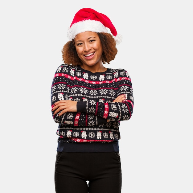 Junge schwarze Frau in einer modischen Weihnachtsstrickjacke mit den Drucküberfahrtarmen, lächelnd und entspannt